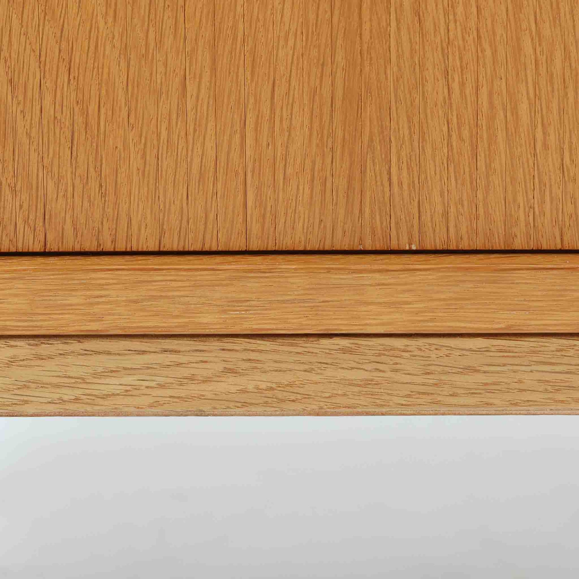 Poul Hundevadがデザインし、Hundevad &amp; Coより製作された蛇腹仕様のサイドボードです。オーク材の穏やかで上品な木目を活かした外観に、横方向へ滑らかに開閉する蛇腹扉を組み合わせた、機能美あふれる一台。扉の開閉時に前後のスペースを取らない構造は、動線を妨げず実用性にも優れています。内部は棚板構成で収納力が高く、食器や書類、リビング周りの小物まで幅広く対応。細身の脚部が全体を軽やかに引き締め、経年によって深みを増した素材感が北欧ビンテージならではの静かな存在感を空間にもたらします。