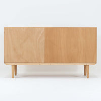 Poul Hundevadがデザインし、Hundevad & Coより製作された蛇腹仕様のサイドボードです。オーク材の穏やかで上品な木目を活かした外観に、横方向へ滑らかに開閉する蛇腹扉を組み合わせた、機能美あふれる一台。扉の開閉時に前後のスペースを取らない構造は、動線を妨げず実用性にも優れています。内部は棚板構成で収納力が高く、食器や書類、リビング周りの小物まで幅広く対応。細身の脚部が全体を軽やかに引き締め、経年によって深みを増した素材感が北欧ビンテージならではの静かな存在感を空間にもたらします。