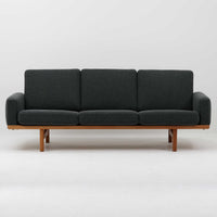 Hans J. Wegnerがデザインし、Getamaより製作された「GE236」トリプルソファです。オーク材のフレームに、背面の横桟が美しく並ぶ構造が特徴で、後ろ姿まで洗練された佇まいを見せるウェグナーらしいデザイン。クッション内部にはスプリングが内包されており、程よい弾力と快適な座り心地を実現しています。落ち着いた色合いの張地が木部の温かな表情を引き立てる、北欧ビンテージを代表する名作ソファです。