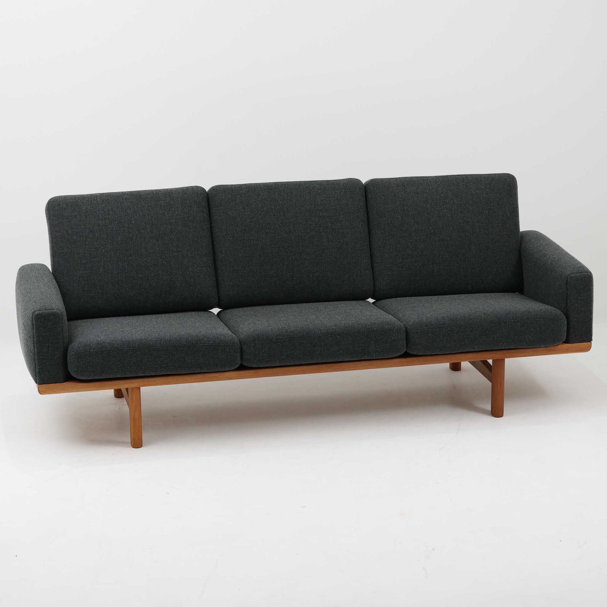 Hans J. Wegnerがデザインし、Getamaより製作された「GE236」トリプルソファです。オーク材のフレームに、背面の横桟が美しく並ぶ構造が特徴で、後ろ姿まで洗練された佇まいを見せるウェグナーらしいデザイン。クッション内部にはスプリングが内包されており、程よい弾力と快適な座り心地を実現しています。落ち着いた色合いの張地が木部の温かな表情を引き立てる、北欧ビンテージを代表する名作ソファです。