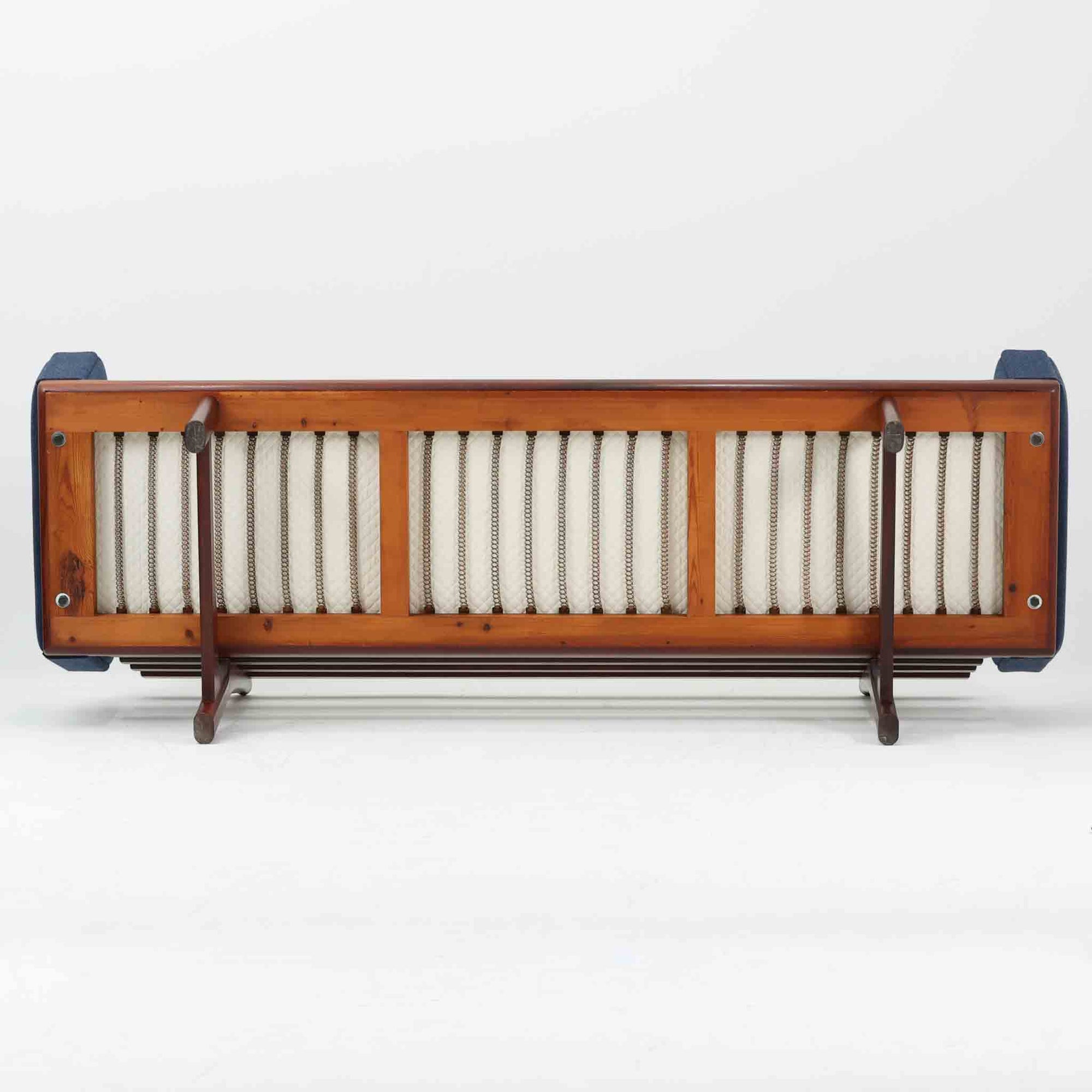 こちらは、ウェグナーデザインの人気モデル、GE236の3人掛けソファです。後ろ姿が非常に美しいため、あえて壁に寄せず背面を見せる配置もおすすめです。クッション内部にはスプリングが内蔵されており、座り心地も良好です。さらに、こちらは現地でも希少なアフロモシア材（通称アフリカンチーク）が使用された特別なモデルです。GE236のチーク材仕様として一般的に認識されているのは、このアフロモシア材が使用されたモデルを指します。GETAMA社の刻印も確認できます。