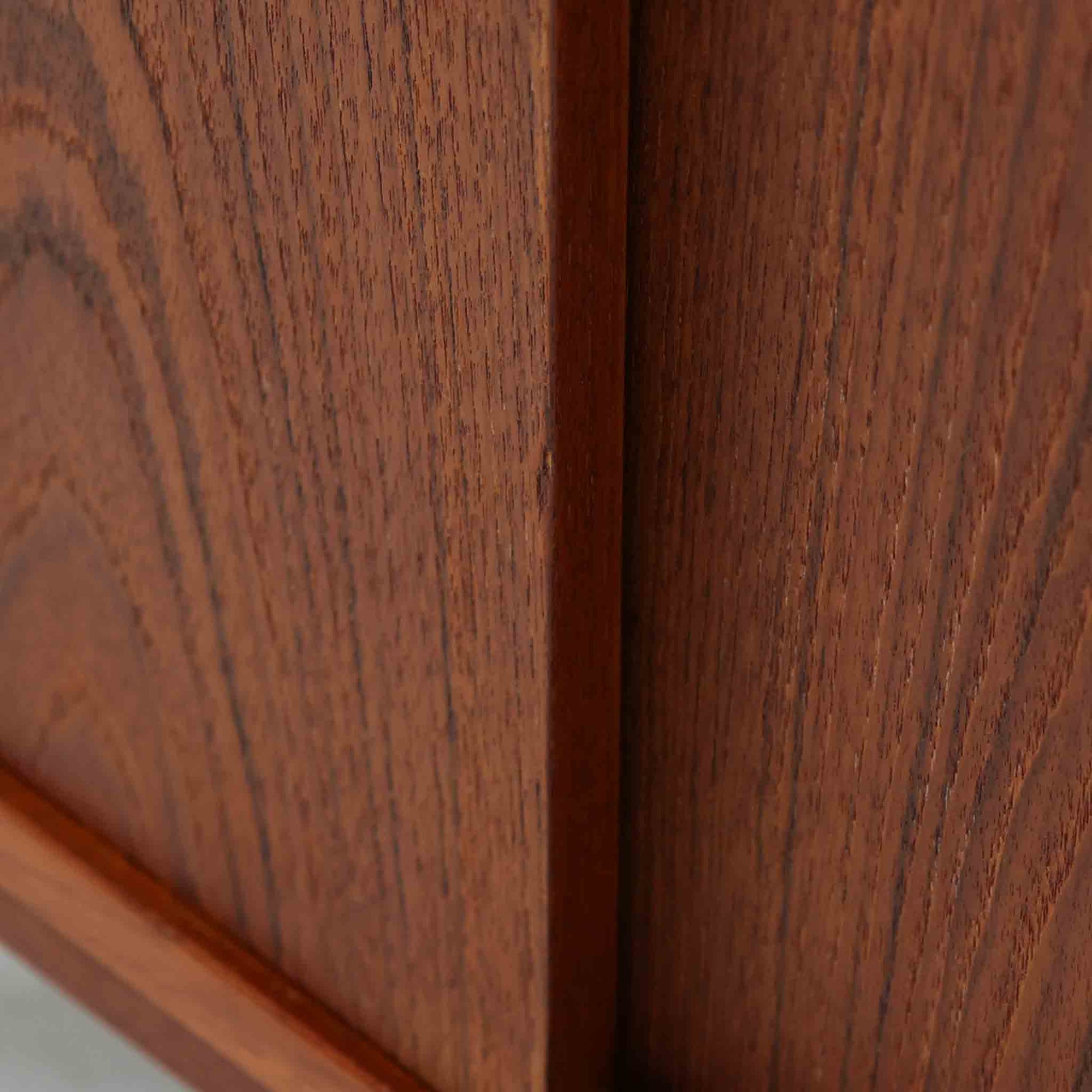 デンマーク製ローボードです。チーク材ならではの赤みを帯びた美しい木目が前面にあらわれ、引き戸には掘り込み式の丸い取っ手を配したミニマルな意匠が北欧らしい静かな存在感を放ちます。幅80cmの小ぶりなサイズ感で、リビングのテレビ台としてはもちろん、書斎やベッドルームでの収納家具としても取り入れやすく、内部には棚板を備え実用性も十分です。経年によって深みを増した木肌の表情と丁寧なつくりが、ビンテージならではの温もりを空間に添えてくれる一台です。