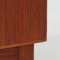 デンマーク製ローボードです。チーク材ならではの赤みを帯びた美しい木目が前面にあらわれ、引き戸には掘り込み式の丸い取っ手を配したミニマルな意匠が北欧らしい静かな存在感を放ちます。幅80cmの小ぶりなサイズ感で、リビングのテレビ台としてはもちろん、書斎やベッドルームでの収納家具としても取り入れやすく、内部には棚板を備え実用性も十分です。経年によって深みを増した木肌の表情と丁寧なつくりが、ビンテージならではの温もりを空間に添えてくれる一台です。