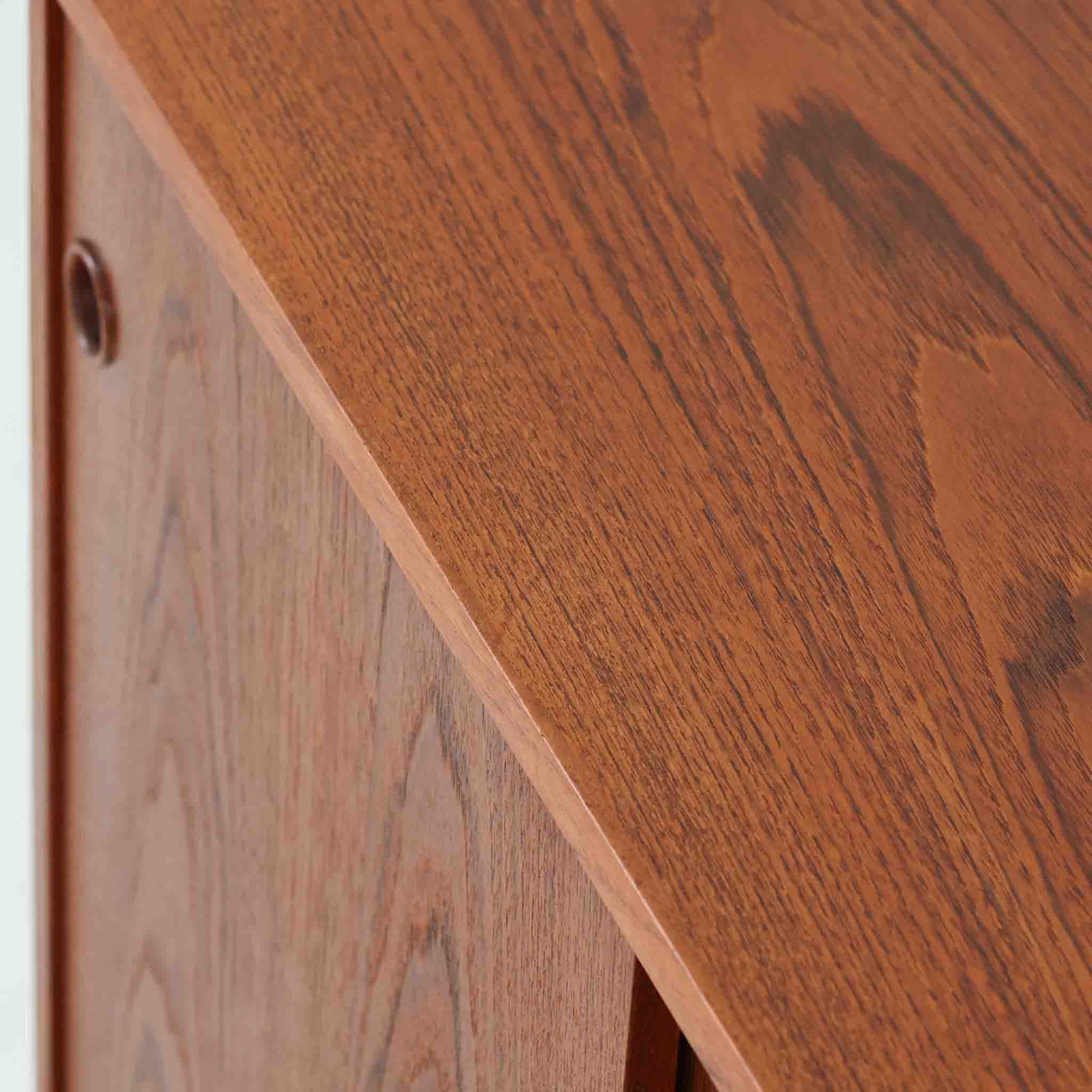 デンマーク製ローボードです。チーク材ならではの赤みを帯びた美しい木目が前面にあらわれ、引き戸には掘り込み式の丸い取っ手を配したミニマルな意匠が北欧らしい静かな存在感を放ちます。幅80cmの小ぶりなサイズ感で、リビングのテレビ台としてはもちろん、書斎やベッドルームでの収納家具としても取り入れやすく、内部には棚板を備え実用性も十分です。経年によって深みを増した木肌の表情と丁寧なつくりが、ビンテージならではの温もりを空間に添えてくれる一台です。