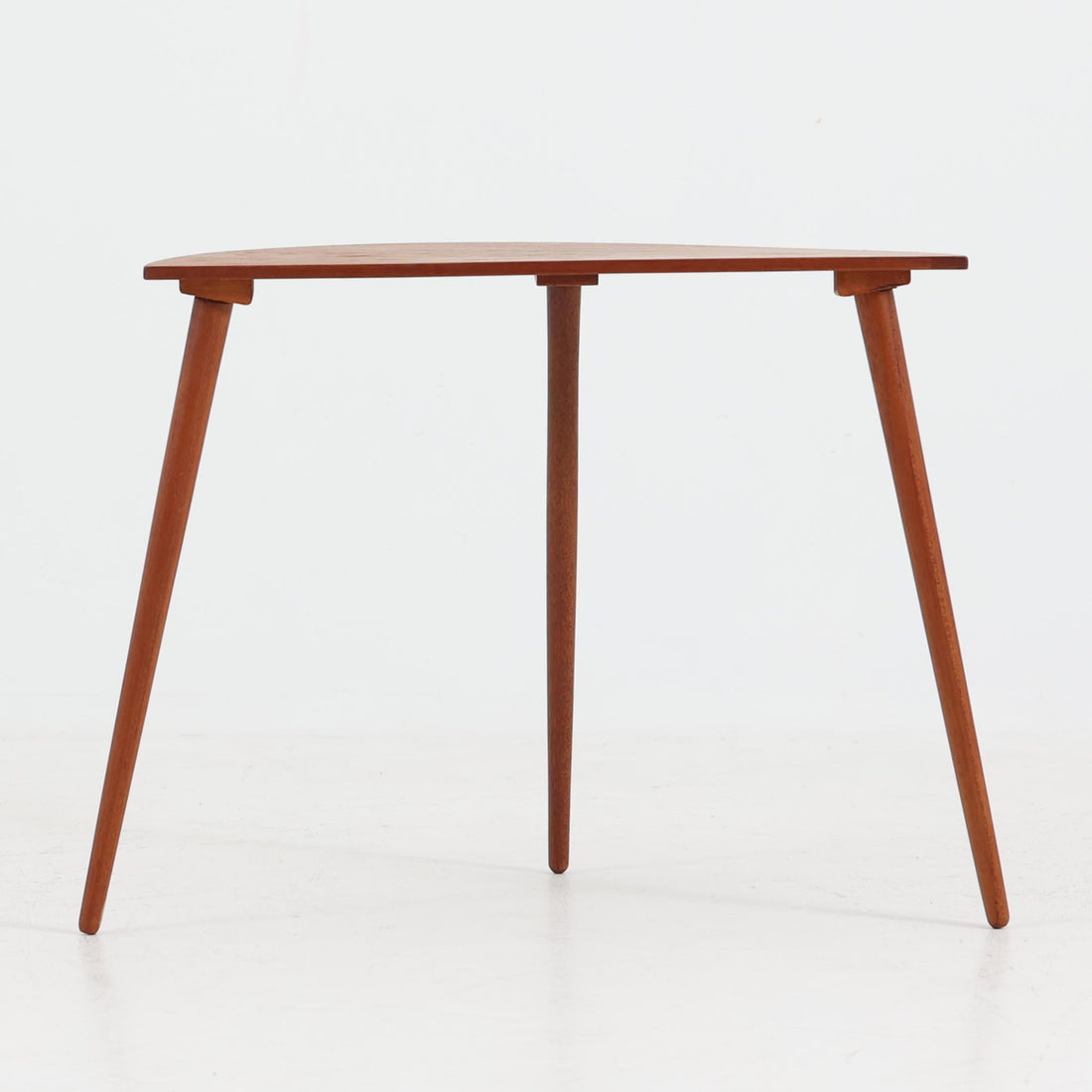 デンマーク製サイドテーブルです。チーク材を使用し、滑らかな半円形の天板とすらりと伸びた3本の円錐脚が軽やかな印象を与えます。北欧デザインらしいミニマルな造形ながら、チーク材の温かみと艶が経年変化によって美しく際立っています。ソファ横やベッドサイドなど、限られたスペースにも馴染むサイズ感で、花瓶やランプを置く飾り台としてもおすすめの一台です。