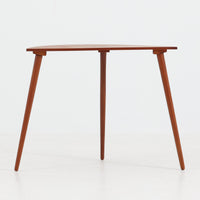 デンマーク製サイドテーブルです。チーク材を使用し、滑らかな半円形の天板とすらりと伸びた3本の円錐脚が軽やかな印象を与えます。北欧デザインらしいミニマルな造形ながら、チーク材の温かみと艶が経年変化によって美しく際立っています。ソファ横やベッドサイドなど、限られたスペースにも馴染むサイズ感で、花瓶やランプを置く飾り台としてもおすすめの一台です。