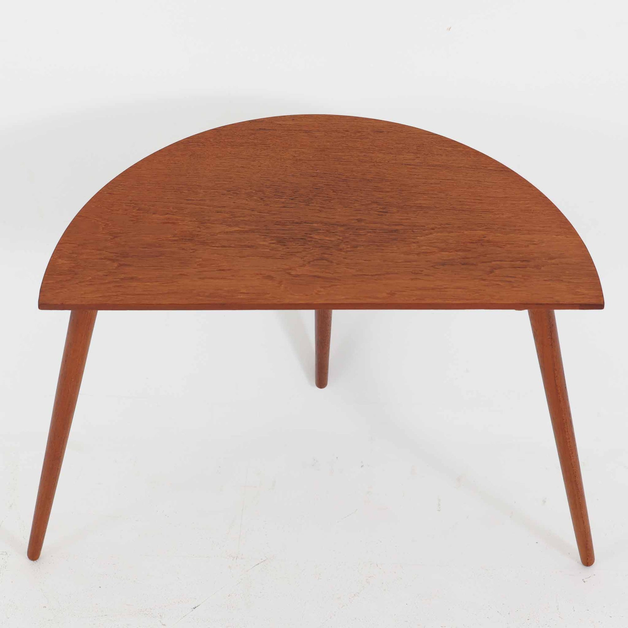 デンマーク製サイドテーブルです。チーク材を使用し、滑らかな半円形の天板とすらりと伸びた3本の円錐脚が軽やかな印象を与えます。北欧デザインらしいミニマルな造形ながら、チーク材の温かみと艶が経年変化によって美しく際立っています。ソファ横やベッドサイドなど、限られたスペースにも馴染むサイズ感で、花瓶やランプを置く飾り台としてもおすすめの一台です。