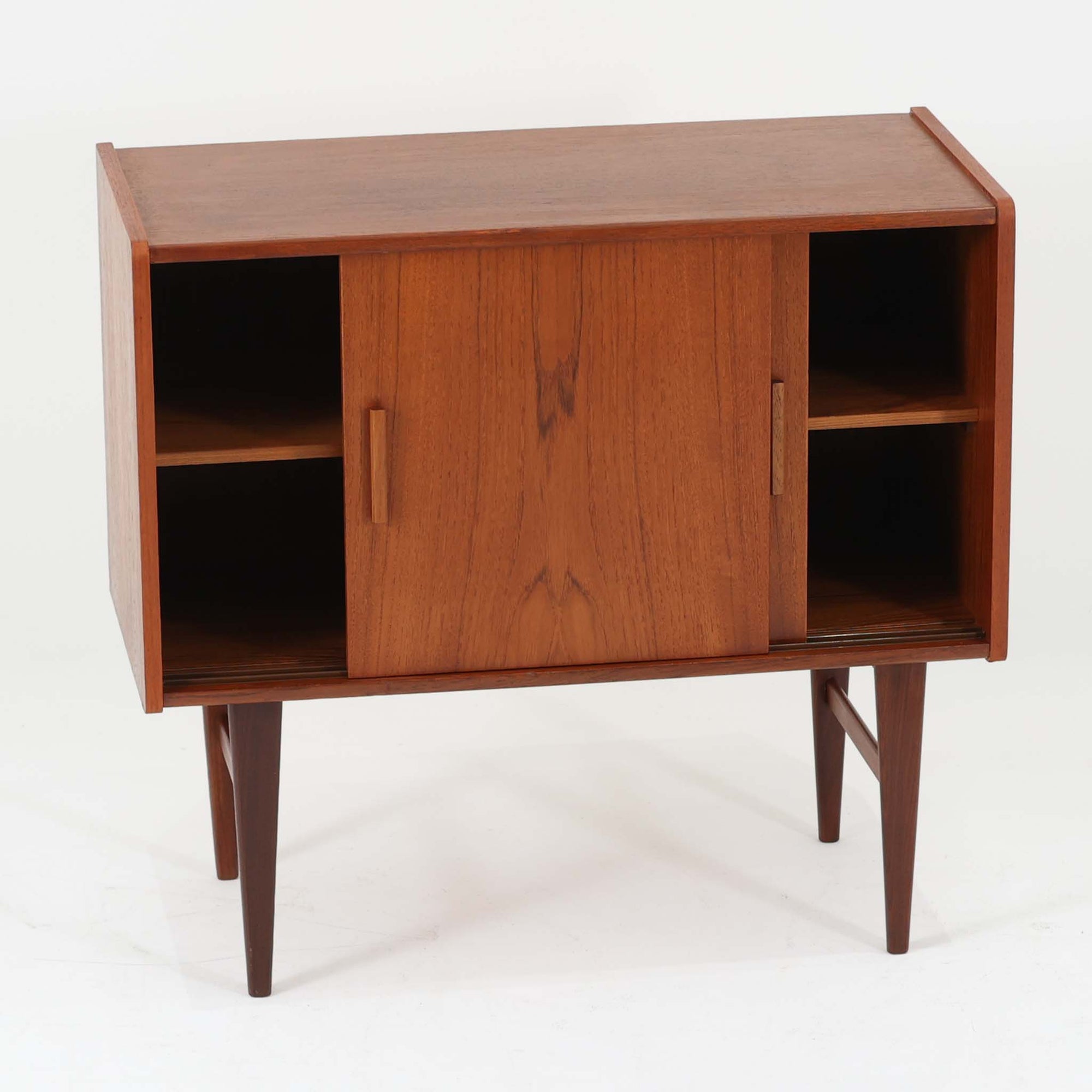 北欧ビンテージらしい端正な佇まいが魅力の小ぶりなボードです。深みのある色合いが美しいチーク材が用いられ、木目の表情と経年変化による艶感が空間に落ち着きを与えます。引き戸仕様の扉は前後にスペースを取らず、限られた空間でも扱いやすい構造です。内部には棚板を備え、食器や書類、小物類まですっきりと収納可能。幅80cmのコンパクトなサイズ感は、リビングのサブ収納や玄関、書斎など多用途に活躍し、北欧家具ならではの実用性と素材の良さを感じさせる一台です。