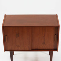 北欧ビンテージらしい端正な佇まいが魅力の小ぶりなボードです。深みのある色合いが美しいチーク材が用いられ、木目の表情と経年変化による艶感が空間に落ち着きを与えます。引き戸仕様の扉は前後にスペースを取らず、限られた空間でも扱いやすい構造です。内部には棚板を備え、食器や書類、小物類まですっきりと収納可能。幅80cmのコンパクトなサイズ感は、リビングのサブ収納や玄関、書斎など多用途に活躍し、北欧家具ならではの実用性と素材の良さを感じさせる一台です。