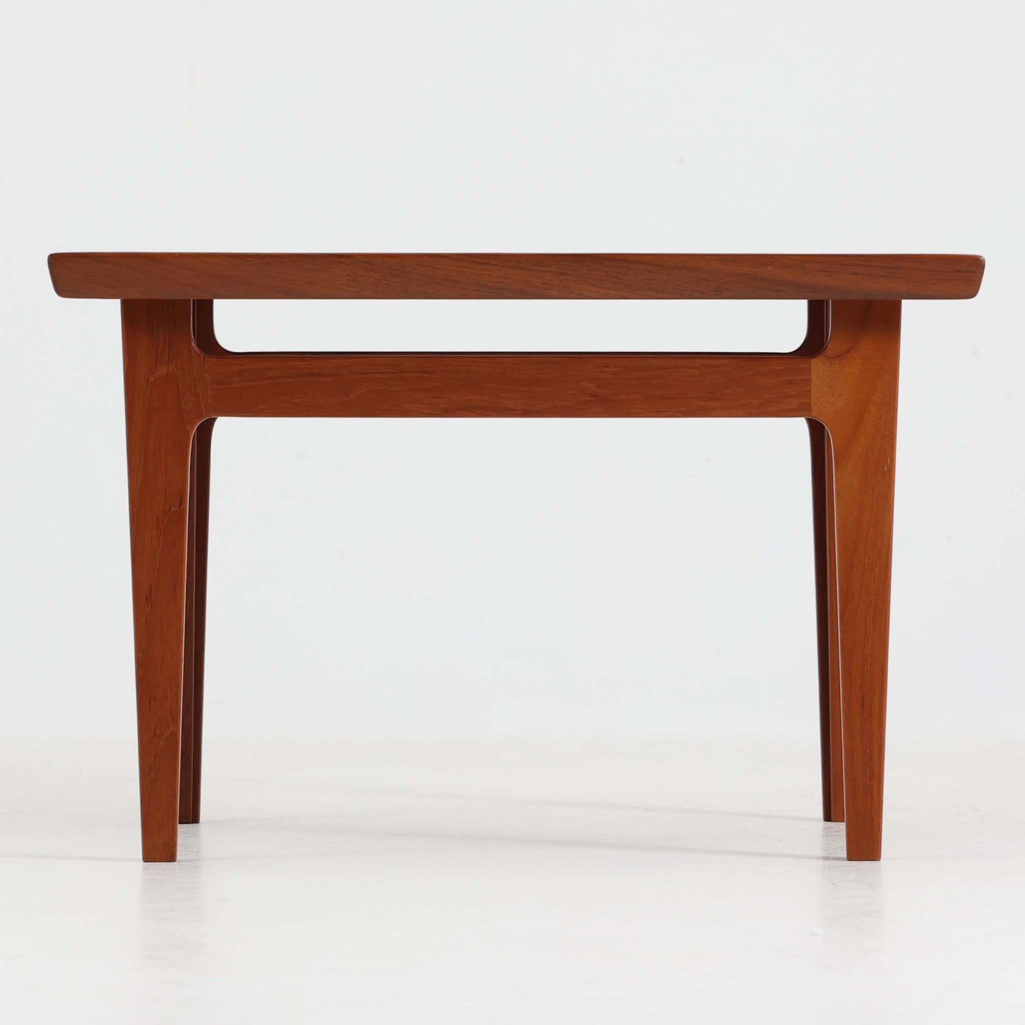 デンマークの巨匠フィン・ユールによるデザイン、France & Son社製のサイドテーブル「FD635」です。ロゴより1957～1960年代前半に製造されたと推測される本品は、チーク無垢材を贅沢に使用し、滑らかな脚部の曲線と柔らかなエッジラインが見事に調和した美しいデザインが魅力です。天板の縁にはわずかな立ち上がりが設けられ、機能性と造形美を兼ね備えた構造となっています。彫刻的ともいえる有機的なフォルムはフィン・ユールの真骨頂であり、リビングやベッドサイドで北欧家具の上質な存在感を引き立てる逸品です。