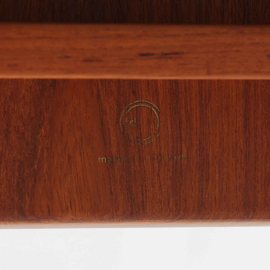 デンマークの巨匠フィン・ユールによるデザイン、France & Son社製のサイドテーブル「FD635」です。ロゴより1957～1960年代前半に製造されたと推測される本品は、チーク無垢材を贅沢に使用し、滑らかな脚部の曲線と柔らかなエッジラインが見事に調和した美しいデザインが魅力です。天板の縁にはわずかな立ち上がりが設けられ、機能性と造形美を兼ね備えた構造となっています。彫刻的ともいえる有機的なフォルムはフィン・ユールの真骨頂であり、リビングやベッドサイドで北欧家具の上質な存在感を引き立てる逸品です。