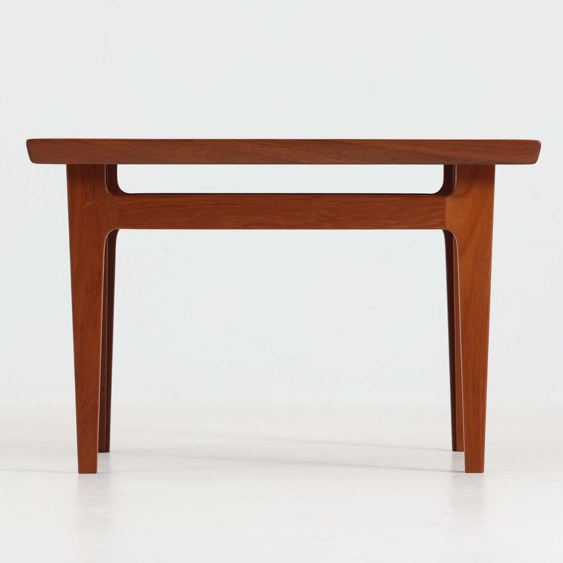 デンマークの巨匠フィン・ユールによるデザイン、France & Son社製のサイドテーブル「FD635」です。ロゴより1957～1960年代前半に製造されたと推測される本品は、チーク無垢材を贅沢に使用し、滑らかな脚部の曲線と柔らかなエッジラインが見事に調和した美しいデザインが魅力です。天板の縁にはわずかな立ち上がりが設けられ、機能性と造形美を兼ね備えた構造となっています。彫刻的ともいえる有機的なフォルムはフィン・ユールの真骨頂であり、リビングやベッドサイドで北欧家具の上質な存在感を引き立てる逸品です。