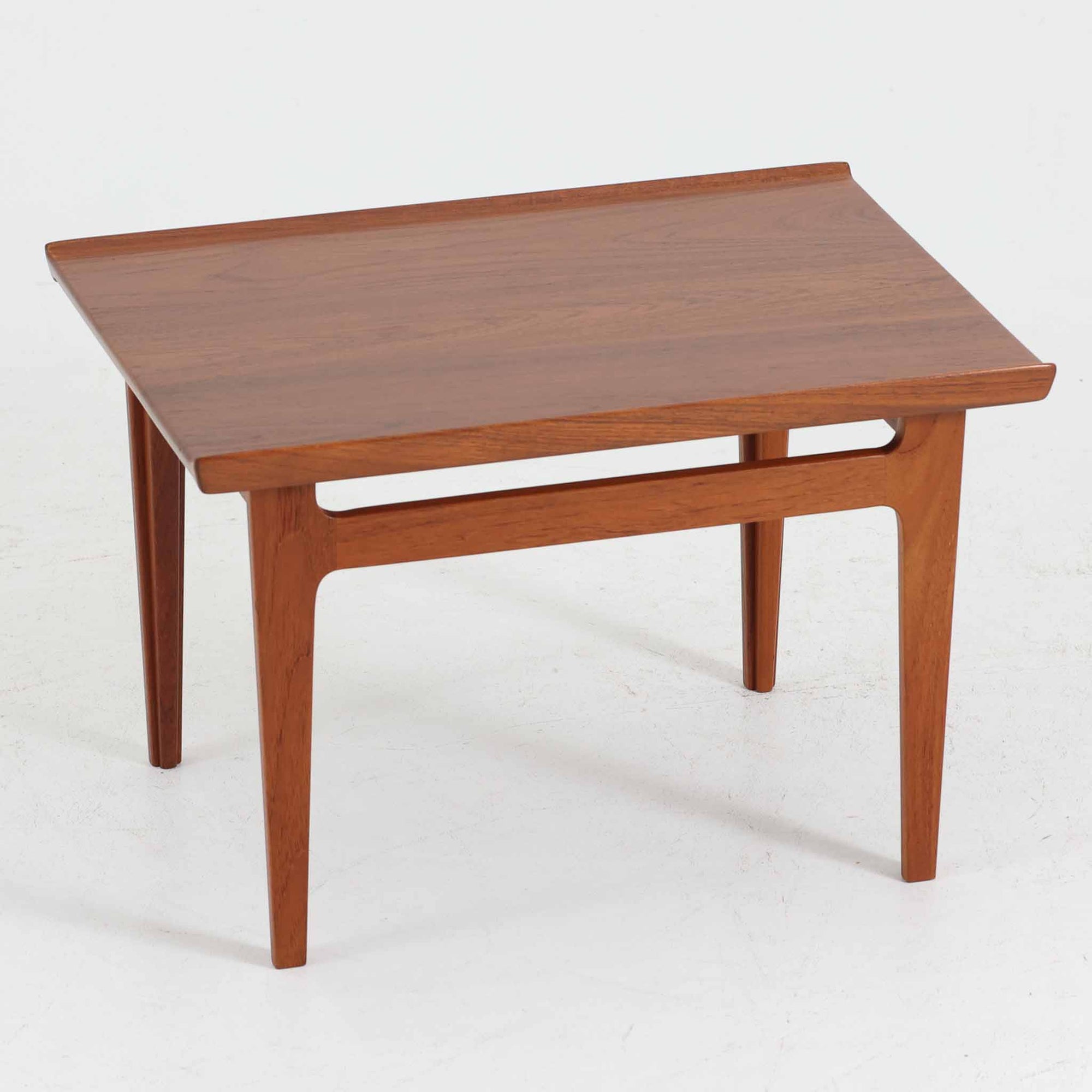 デンマークの巨匠フィン・ユールによるデザイン、France &amp; Son社製のサイドテーブル「FD635」です。ロゴより1957～1960年代前半に製造されたと推測される本品は、チーク無垢材を贅沢に使用し、滑らかな脚部の曲線と柔らかなエッジラインが見事に調和した美しいデザインが魅力です。天板の縁にはわずかな立ち上がりが設けられ、機能性と造形美を兼ね備えた構造となっています。彫刻的ともいえる有機的なフォルムはフィン・ユールの真骨頂であり、リビングやベッドサイドで北欧家具の上質な存在感を引き立てる逸品です。