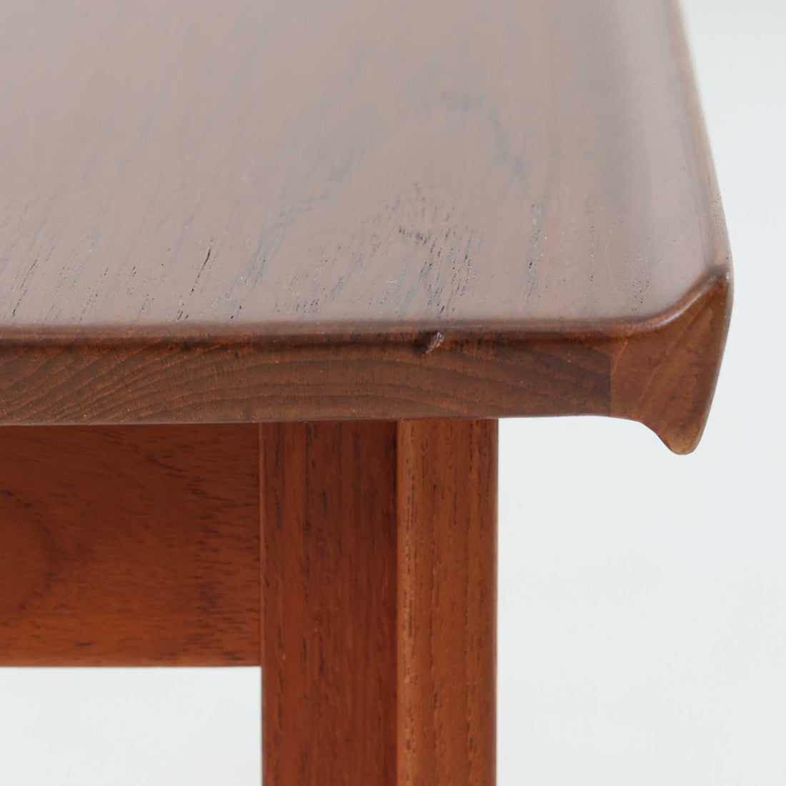 デンマークの巨匠フィン・ユールによるデザイン、France & Son社製のサイドテーブル「FD635」です。ロゴより1957～1960年代前半に製造されたと推測される本品は、チーク無垢材を贅沢に使用し、滑らかな脚部の曲線と柔らかなエッジラインが見事に調和した美しいデザインが魅力です。天板の縁にはわずかな立ち上がりが設けられ、機能性と造形美を兼ね備えた構造となっています。彫刻的ともいえる有機的なフォルムはフィン・ユールの真骨頂であり、リビングやベッドサイドで北欧家具の上質な存在感を引き立てる逸品です。