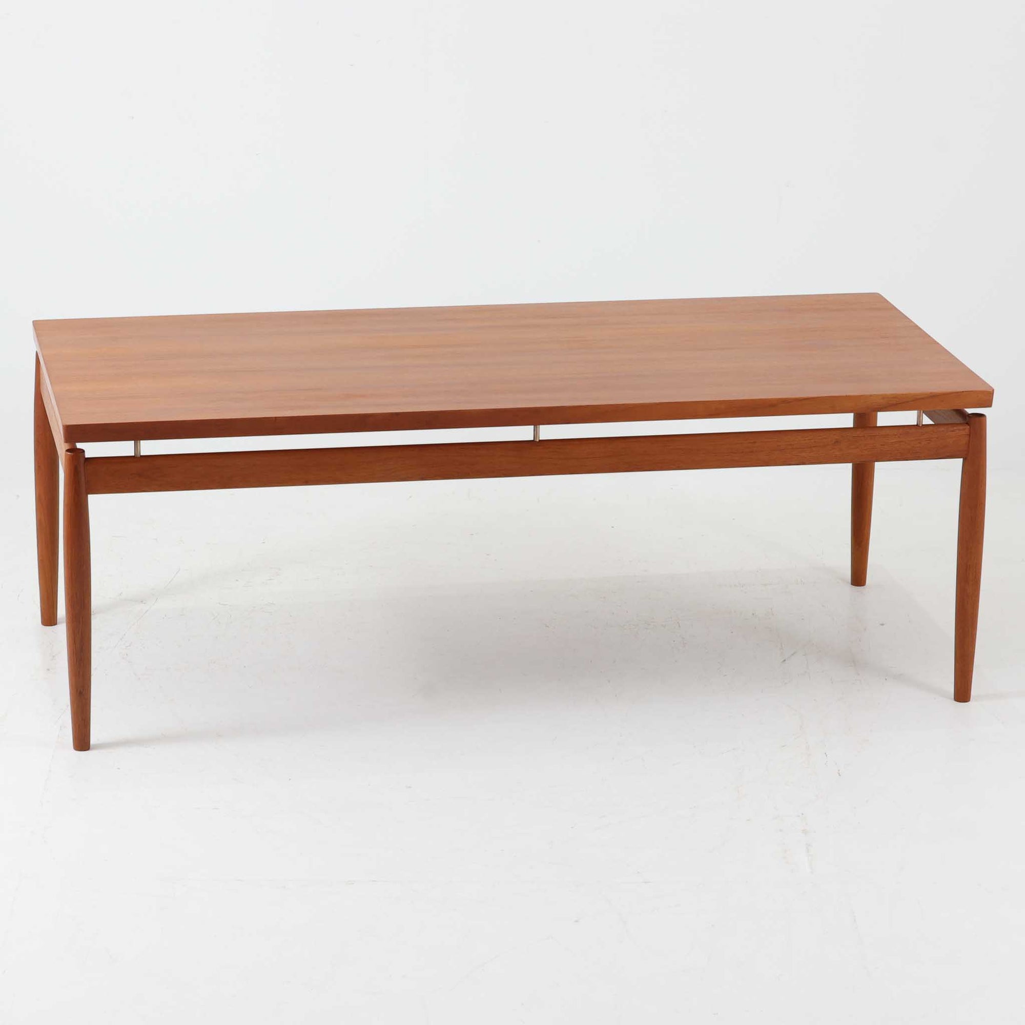 Grete Jalk（グレーテ・ヤルク）によるデザイン、France &amp; Son社製のセンターテーブル Model 622/54です。繊細なテーパードレッグに天板と幕板の隙間を持たせた軽やかな構造が美しく、真鍮パーツがアクセントとして上質な存在感を添えています。幅150cmのゆったりとしたサイズはリビングでの使用に最適で、ソファ前のテーブルとしてはもちろん展示台としてもバランスよく馴染みます。北欧モダンを象徴する端正なラインとチーク材の豊かな木目が魅力で、ロゴプレートの仕様より1960年代半ば〜1969年頃に製造された個体と推測され、ミッドセンチュリー期を代表する名作ビンテージ家具です。