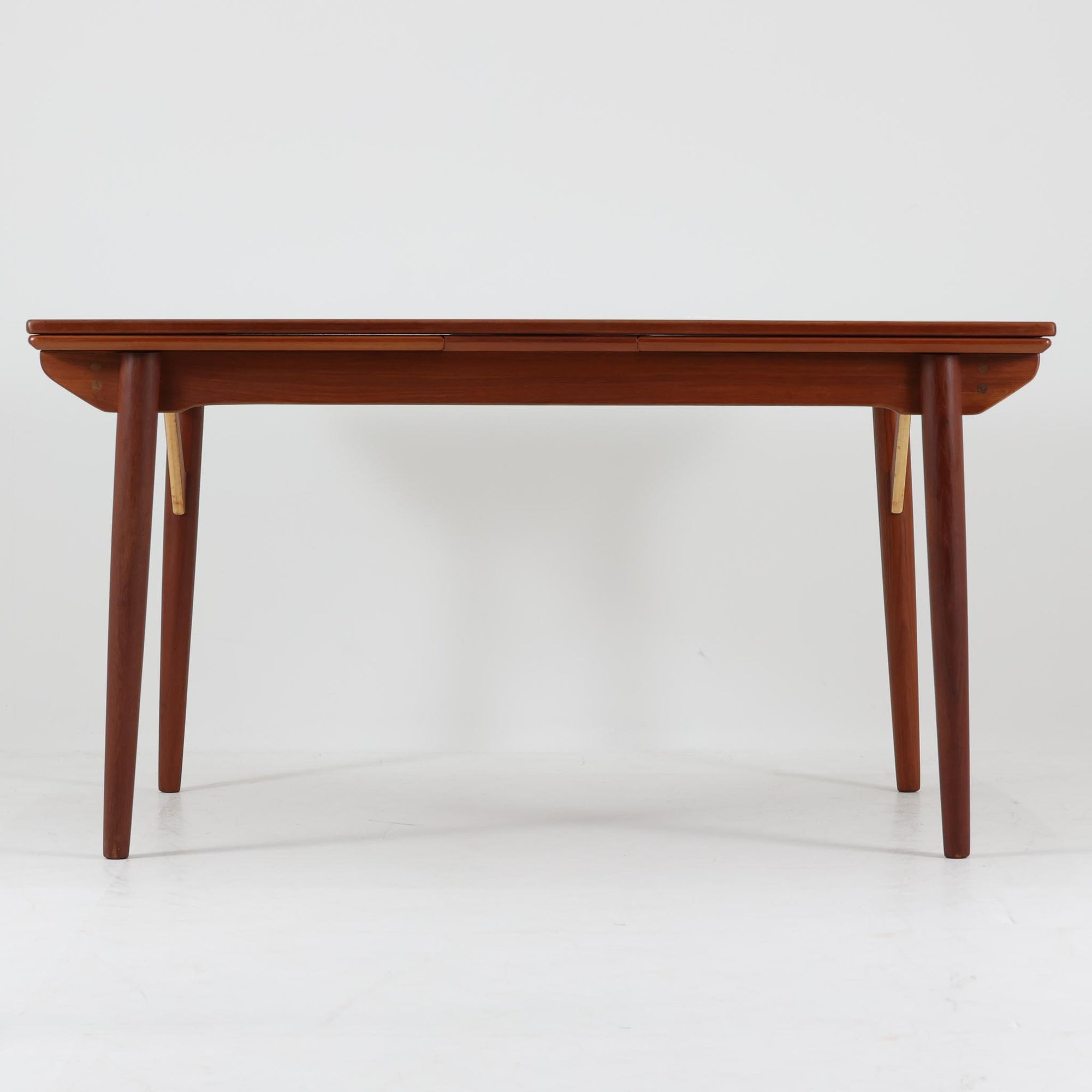 エクステンションダイニングテーブルです。良質な木材ならではの美しい木目と経年により深みを増した色艶が魅力で、天板下に収められた拡張板を引き出すことで用途に応じてサイズを調整できる実用的な構造となっています。天板縁のやわらかな丸みや幕板の緩やかなカーブに加え、脚と幕板をつなぐ斜めの補強材がデザインのアクセントとなり、軽やかさと安定感を両立。片側のみの展開も可能で、日常使いから来客時まで柔軟に対応し、空間に温もりと洗練された存在感をもたらします。