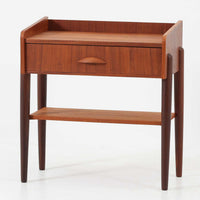 デンマーク製のサイドチェストです。チーク材ならではの温かみある木目と落ち着いた色合いが美しく、側板を立ち上げた天板形状がさりげないデザインアクセントになっています。引き出しには手掛けとして一体成形された取っ手があしらわれ、滑らかな開閉とすっきりとした正面意匠を両立しています。幅52cmの扱いやすいサイズ感で、ベッドサイドやソファ脇、玄関先などにも取り入れやすく、下段の棚板は本や小物の収納にも便利です。経年変化によって深みを増したチークの表情が、ビンテージならではの落ち着いた存在感を空間にもたらします。