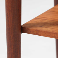 デンマーク製のサイドチェストです。チーク材ならではの温かみある木目と落ち着いた色合いが美しく、側板を立ち上げた天板形状がさりげないデザインアクセントになっています。引き出しには手掛けとして一体成形された取っ手があしらわれ、滑らかな開閉とすっきりとした正面意匠を両立しています。幅52cmの扱いやすいサイズ感で、ベッドサイドやソファ脇、玄関先などにも取り入れやすく、下段の棚板は本や小物の収納にも便利です。経年変化によって深みを増したチークの表情が、ビンテージならではの落ち着いた存在感を空間にもたらします。