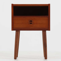 デンマーク製のサイドチェストで、温かみのあるチーク材を用いた北欧ビンテージらしい佇まいが魅力です。上段のオープンスペースは読みかけの本や小物の収納に便利で、下段の引き出しにはアイコン的な丸型取手があしらわれ、シンプルな中にも愛嬌のあるアクセントを添えています。細く伸びたテーパードレッグが軽やかな印象を与え、ベッドサイドやソファ横のサイドテーブルとしても活躍。経年変化による深い色艶が空間に上質な雰囲気をもたらすビンテージ家具です。