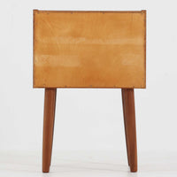 デンマーク製のサイドチェストで、温かみのあるチーク材を用いた北欧ビンテージらしい佇まいが魅力です。上段のオープンスペースは読みかけの本や小物の収納に便利で、下段の引き出しにはアイコン的な丸型取手があしらわれ、シンプルな中にも愛嬌のあるアクセントを添えています。細く伸びたテーパードレッグが軽やかな印象を与え、ベッドサイドやソファ横のサイドテーブルとしても活躍。経年変化による深い色艶が空間に上質な雰囲気をもたらすビンテージ家具です。