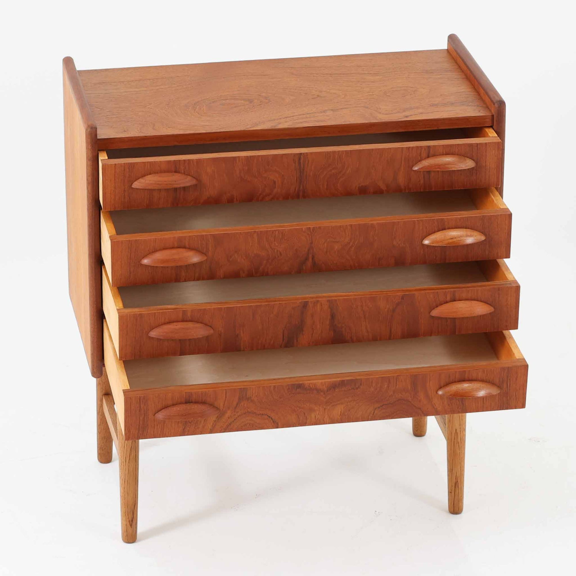 チーク材とオーク材を組み合わせた4段チェストです。前板には美しい木目を持つチーク材、脚部には明るく堅牢なオーク材が用いられ、素材のコントラストが北欧らしい洗練された印象を与えます。緩やかな曲線を描く取手や、すっきりとしたプロポーションが全体を端正にまとめ、コンパクトな幅59cmながら十分な収納力を備えています。リビングや寝室、書斎などさまざまな空間に取り入れやすく、ビンテージならではの風合いと実用性を兼ね備えた一台です。