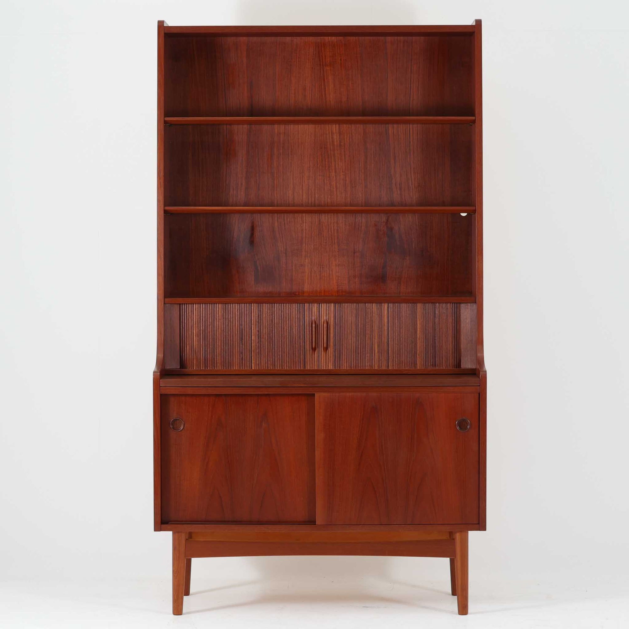 Johannes Sorthがデザインし、Nexo Mobelfabrikが製作したディスプレイシェルフです。美しいチーク材の深みある木目を活かした端正なフォルムに、蛇腹扉を備えた収納部が上質なアクセントとなっています。上部のオープン棚はお気に入りの器や書籍、オブジェを美しく飾ることができ、中段の細かな仕切りや小引き出しは書類や小物整理にも便利。下部の引き戸収納まで備えた実用性の高い構成で、リビングや書斎で見せる収納と隠す収納を両立します。経年で深みを増した木肌と職人技が、北欧ビンテージならではの存在感を放つ希少な一台です。