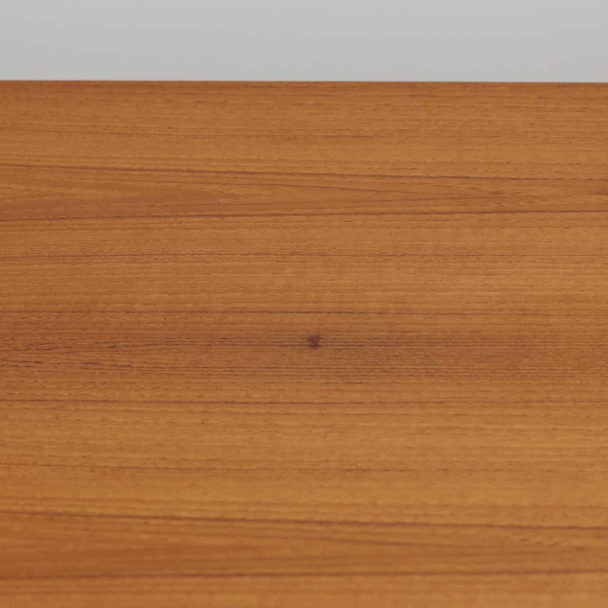 Johannes Andersenがデザインし、C.F.C. Silkeborgが製作した幅200cmのサイドボードです。チーク材の豊かな木目を活かした滑らかな曲面フレームと、横へ流れるように開閉する蛇腹扉が印象的で、端正さの中に軽やかなリズムを生み出します。中央の4段引き出しと両側の収納スペースにより高い収納力を備え、内部の棚板は可動式で実用性も良好。すらりと伸びる脚部が全体に洗練された印象を与え、空間に北欧ビンテージならではの気品と存在感をもたらします。