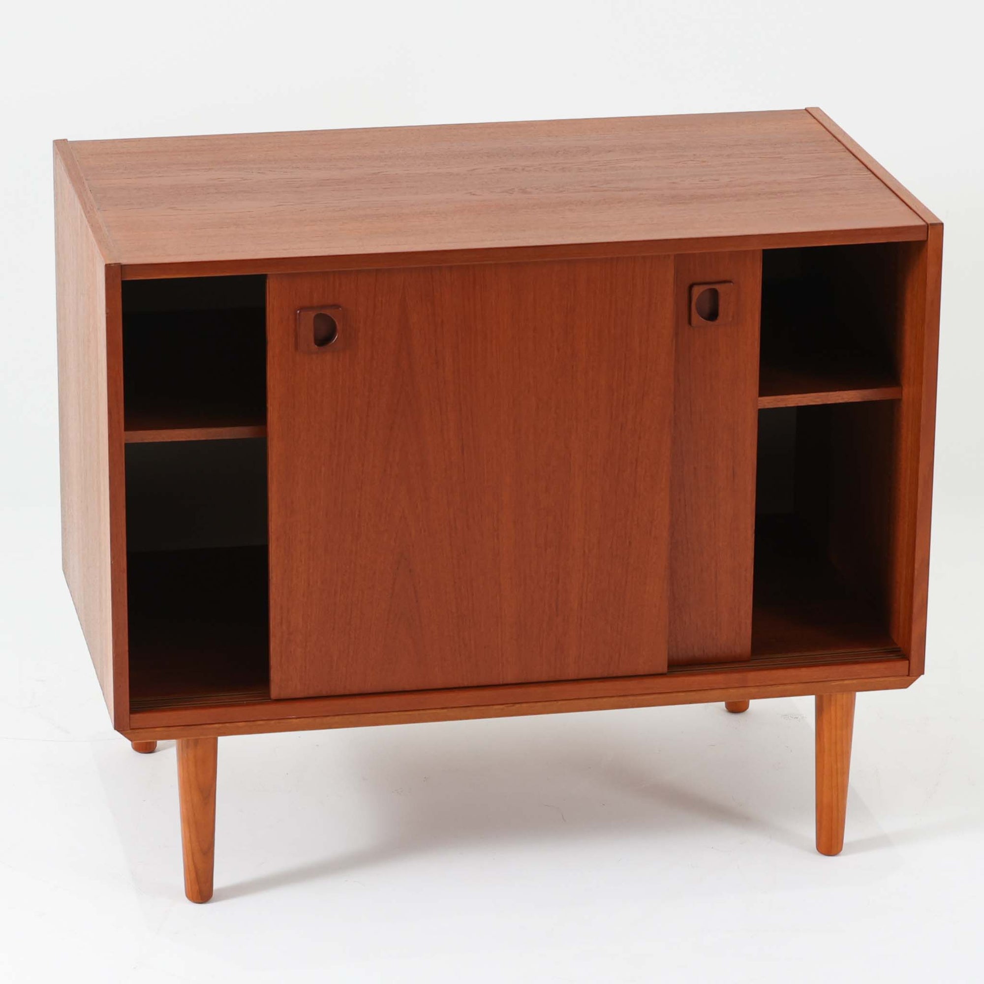 チーク材とビーチ材を組み合わせた北欧ビンテージのローボードで、直線的で端正なフォルムの中に素材の表情が美しく表れた一台です。引き戸仕様の前面は空間をすっきりと見せ、コンパクトなサイズ感ながら内部は左右に分かれた収納構造で、オーディオ機器や書類、小物類まで整理しやすい設計です。脚付き構造による軽やかな佇まいと、経年によって深みを増した木肌の風合いが、当時の丁寧なつくりとビンテージならではの存在感を感じさせ、リビングや書斎、寝室の収納家具として幅広く活躍します。