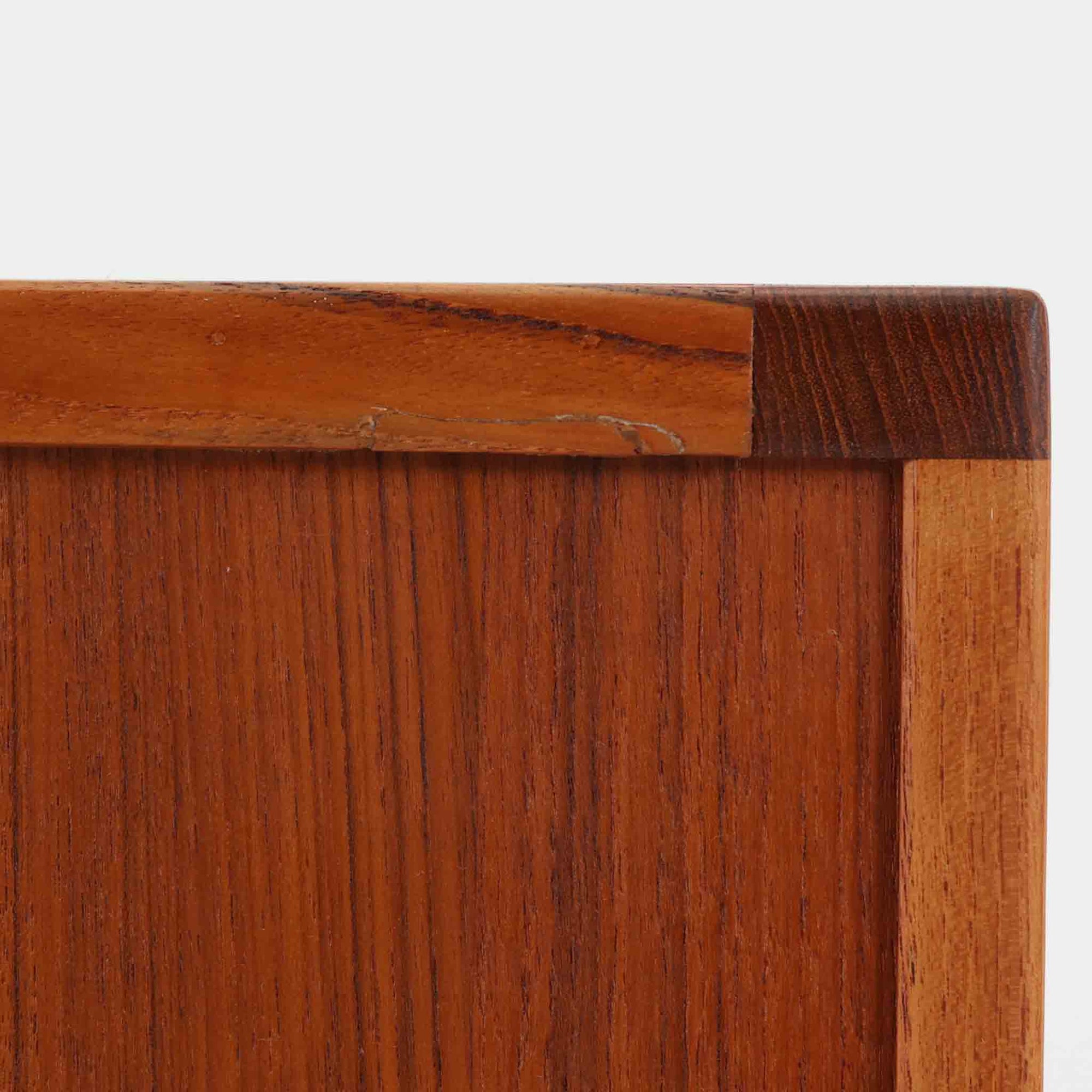 レナート・ベンダーがデザインし、Ulferts Mobler社により製作されたCoronaキャビネットは、小ぶりなサイズ感と端正な佇まいが魅力の北欧ビンテージ家具です。チーク材の美しい木目を活かしたシンプルな箱型構造に、脚部の控えめな意匠が軽やかさを添えています。取っ手部分には異素材となるローズウッドが用いられており、チーク材とのコントラストがさりげないアクセントとして全体の表情を引き締めています。内部は使いやすい収納空間を備え、食器や書類、小物類の整理に適しており、リビングや書斎、玄関周りなど幅広いシーンで活躍します。年月を経て深みを増した素材感と、丁寧な作りが感じられる一台です。