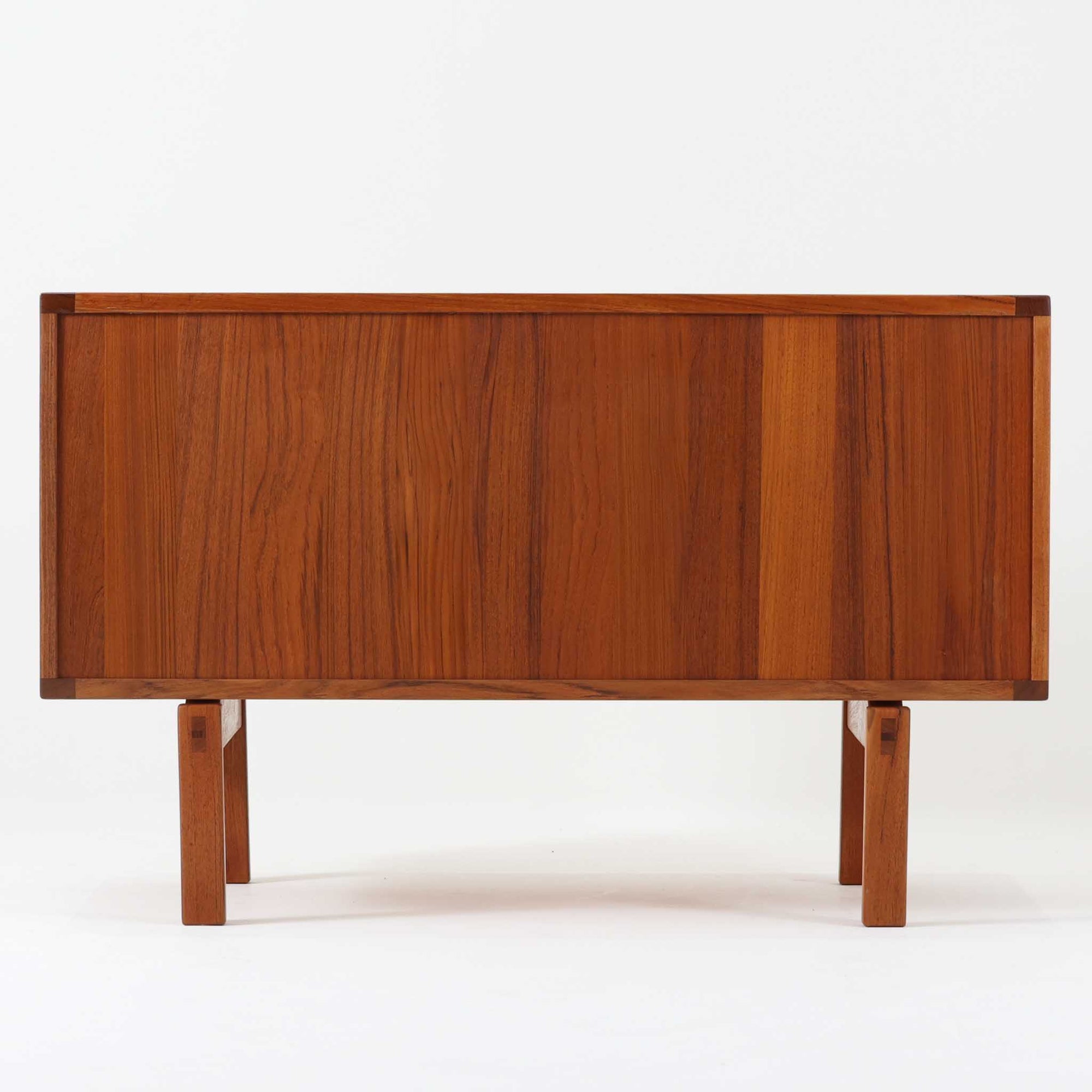 レナート・ベンダーがデザインし、Ulferts Mobler社により製作されたCoronaキャビネットは、小ぶりなサイズ感と端正な佇まいが魅力の北欧ビンテージ家具です。チーク材の美しい木目を活かしたシンプルな箱型構造に、脚部の控えめな意匠が軽やかさを添えています。取っ手部分には異素材となるローズウッドが用いられており、チーク材とのコントラストがさりげないアクセントとして全体の表情を引き締めています。内部は使いやすい収納空間を備え、食器や書類、小物類の整理に適しており、リビングや書斎、玄関周りなど幅広いシーンで活躍します。年月を経て深みを増した素材感と、丁寧な作りが感じられる一台です。