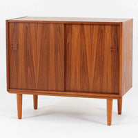 スウェーデン製ボードです。チーク材の温かみある木目を活かしたシンプルな箱型フォルムに、小ぶりな取っ手が愛らしいアクセントとなっています。引き戸仕様のため開閉スペースを取らず、内部には棚板を備え実用性も良好。幅88cmのコンパクトなサイズ感で、リビングや玄関、寝室など様々な空間に取り入れやすい一台です。経年により深みを増した木肌が北欧ビンテージならではの落ち着いた存在感を演出します。