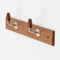 チーク材のベースにメタルフックを組み合わせたデンマーク製の2連ウォールハンガーで、先端には丸みのある木製キャップが付いており掛けた衣類やバッグに優しく、シンプルながら北欧ビンテージらしい温かみのある素材感が魅力です。玄関や寝室、キッチン、ワークスペースなど壁面収納として幅広く活躍し、単体使いはもちろん複数並べて設置することで統一感のあるディスプレイも楽しめます。コンパクトで設置しやすく暮らしの中で気軽に取り入れやすいアイテムです。