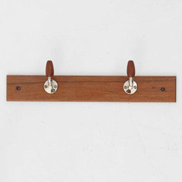 チーク材のベースにメタルフックを組み合わせたデンマーク製の2連ウォールハンガーで、先端には丸みのある木製キャップが付いており掛けた衣類やバッグに優しく、シンプルながら北欧ビンテージらしい温かみのある素材感が魅力です。玄関や寝室、キッチン、ワークスペースなど壁面収納として幅広く活躍し、単体使いはもちろん複数並べて設置することで統一感のあるディスプレイも楽しめます。コンパクトで設置しやすく暮らしの中で気軽に取り入れやすいアイテムです。