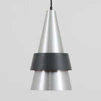 Jo HammerborgがFog & Morupのために手掛けた「Corona」は、直径22cmとコンパクトながら全高45cmと縦にしっかりとした存在感を持つアルミ×スチール製ペンダントライトで、上下に伸びる円錐形フォルムと中央のブラックバンドが彫刻的な印象を与える北欧ビンテージ品です。光源を囲む二重構造によって眩しさを抑えつつ下方向へ明かりを集中的に落とす設計となっており、ダイニングやカウンター上での1灯使用はもちろん、複数灯を並べても空間にリズムを生み出します。経年で深まった素材の風合いがハーマボーらしいモダンな佇まいを際立たせ、空間のアクセントとしても十分な存在感を発揮します。