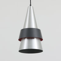 Jo HammerborgがFog & Morupのために手掛けた「Corona」は、直径22cmとコンパクトながら全高45cmと縦にしっかりとした存在感を持つアルミ×スチール製ペンダントライトで、上下に伸びる円錐形フォルムと中央のブラックバンドが彫刻的な印象を与える北欧ビンテージ品です。光源を囲む二重構造によって眩しさを抑えつつ下方向へ明かりを集中的に落とす設計となっており、ダイニングやカウンター上での1灯使用はもちろん、複数灯を並べても空間にリズムを生み出します。経年で深まった素材の風合いがハーマボーらしいモダンな佇まいを際立たせ、空間のアクセントとしても十分な存在感を発揮します。