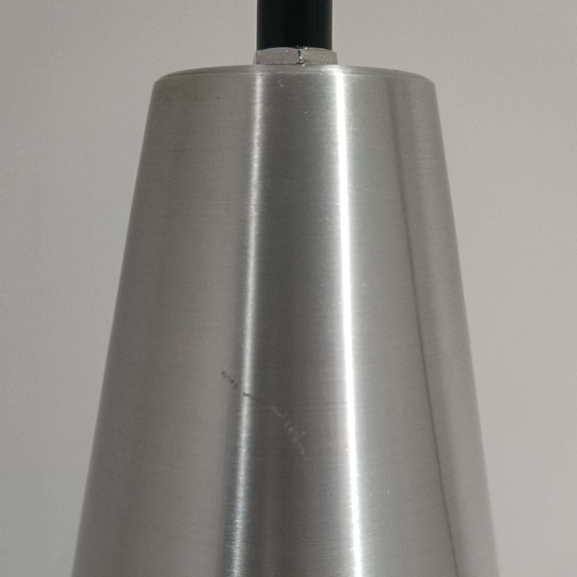 Jo HammerborgがFog &amp; Morupのために手掛けた「Corona」は、直径22cmとコンパクトながら全高45cmと縦にしっかりとした存在感を持つアルミ×スチール製ペンダントライトで、上下に伸びる円錐形フォルムと中央のブラックバンドが彫刻的な印象を与える北欧ビンテージ品です。光源を囲む二重構造によって眩しさを抑えつつ下方向へ明かりを集中的に落とす設計となっており、ダイニングやカウンター上での1灯使用はもちろん、複数灯を並べても空間にリズムを生み出します。経年で深まった素材の風合いがハーマボーらしいモダンな佇まいを際立たせ、空間のアクセントとしても十分な存在感を発揮します。