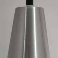 Jo HammerborgがFog & Morupのために手掛けた「Corona」は、直径22cmとコンパクトながら全高45cmと縦にしっかりとした存在感を持つアルミ×スチール製ペンダントライトで、上下に伸びる円錐形フォルムと中央のブラックバンドが彫刻的な印象を与える北欧ビンテージ品です。光源を囲む二重構造によって眩しさを抑えつつ下方向へ明かりを集中的に落とす設計となっており、ダイニングやカウンター上での1灯使用はもちろん、複数灯を並べても空間にリズムを生み出します。経年で深まった素材の風合いがハーマボーらしいモダンな佇まいを際立たせ、空間のアクセントとしても十分な存在感を発揮します。