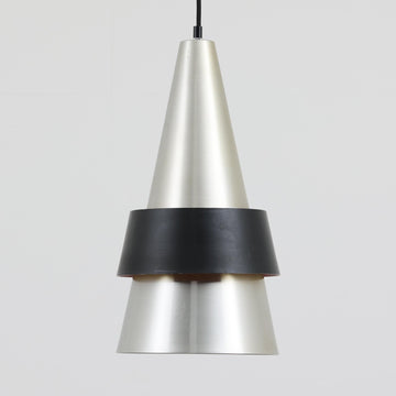 Jo HammerborgがFog & Morupのために手掛けた「Corona」は、直径22cmとコンパクトながら全高45cmと縦にしっかりとした存在感を持つアルミ×スチール製ペンダントライトで、上下に伸びる円錐形フォルムと中央のブラックバンドが彫刻的な印象を与える北欧ビンテージ品です。光源を囲む二重構造によって眩しさを抑えつつ下方向へ明かりを集中的に落とす設計となっており、ダイニングやカウンター上での1灯使用はもちろん、複数灯を並べても空間にリズムを生み出します。経年で深まった素材の風合いがハーマボーらしいモダンな佇まいを際立たせ、空間のアクセントとしても十分な存在感を発揮します。