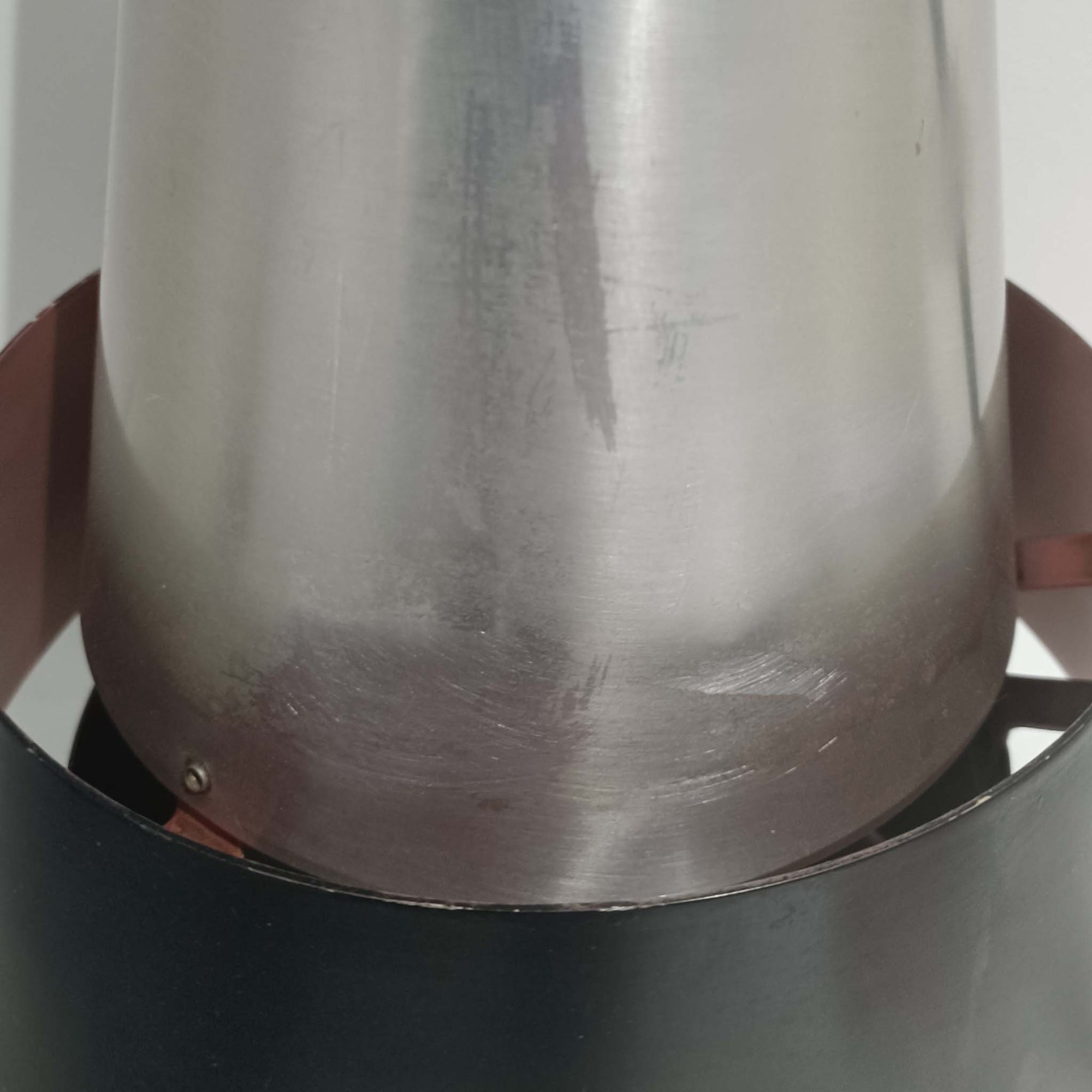 Jo HammerborgがFog &amp; Morupのために手掛けた「Corona」は、直径22cmとコンパクトながら全高45cmと縦にしっかりとした存在感を持つアルミ×スチール製ペンダントライトで、上下に伸びる円錐形フォルムと中央のブラックバンドが彫刻的な印象を与える北欧ビンテージ品です。光源を囲む二重構造によって眩しさを抑えつつ下方向へ明かりを集中的に落とす設計となっており、ダイニングやカウンター上での1灯使用はもちろん、複数灯を並べても空間にリズムを生み出します。経年で深まった素材の風合いがハーマボーらしいモダンな佇まいを際立たせ、空間のアクセントとしても十分な存在感を発揮します。