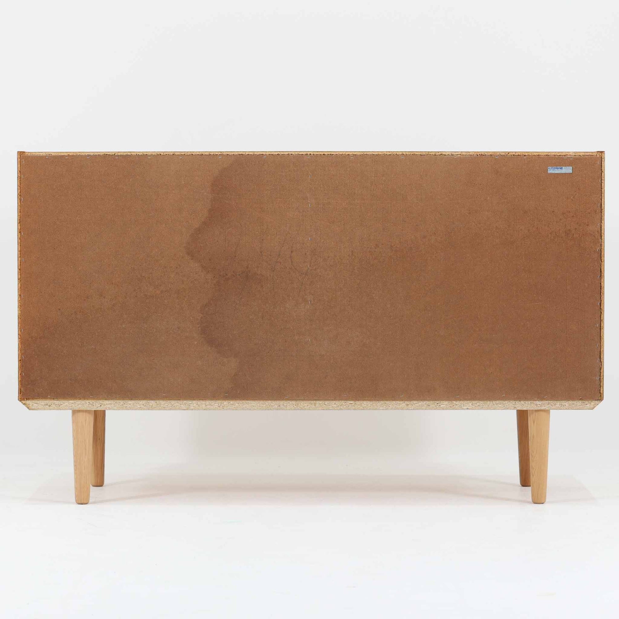 Domino Moblerが製作したデンマーク製ボードです。オーク材の明るく穏やかな木目を活かした端正なフレームです。引き戸構造により省スペースで使いやすく、内部には棚板を備え日用品や書類、食器などをすっきりと収納可能。幅122cmのバランスの取れたサイズ感で、リビングやダイニングのサイドキャビネットとしても活躍します。経年で味わいを増した木肌が空間に温もりと北欧ビンテージらしい趣を添える一品です。