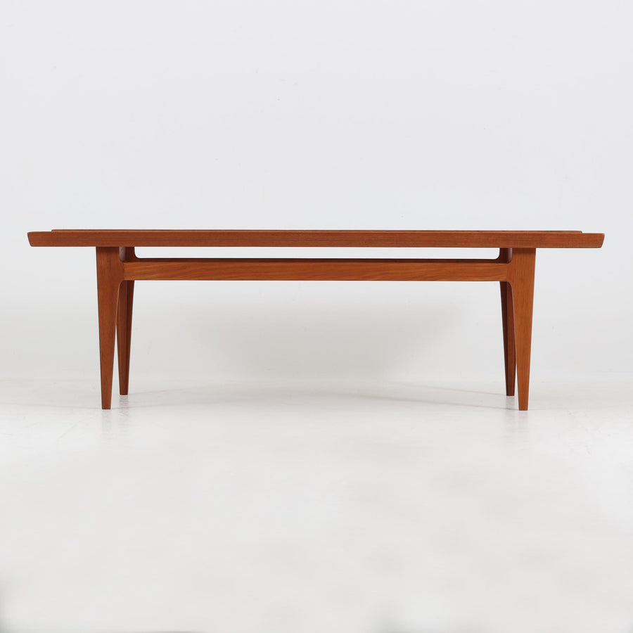 デンマークの名匠フィン・ユールによるデザイン、France & Son社製（前身のFrance & Daverkosen時代に製造）センターテーブル「FD532」です。1950～1957年頃の製造と推測され、チーク無垢材を贅沢に用いた質感豊かな仕上がりが魅力です。脚部から幕板にかけての有機的な曲線や彫刻的なフォルムはフィン・ユールならではの造形美を感じさせ、天板縁のわずかな立ち上がりが軽やかな印象を与えます。FD532には複数の高さバリエーションが存在しますが、本品は低めの約45cmモデルで、ソファ前に合わせやすいバランスの取れたサイズ感。北欧家具らしい温もりと職人技が融合した、希少かつ上質なビンテージテーブルです。