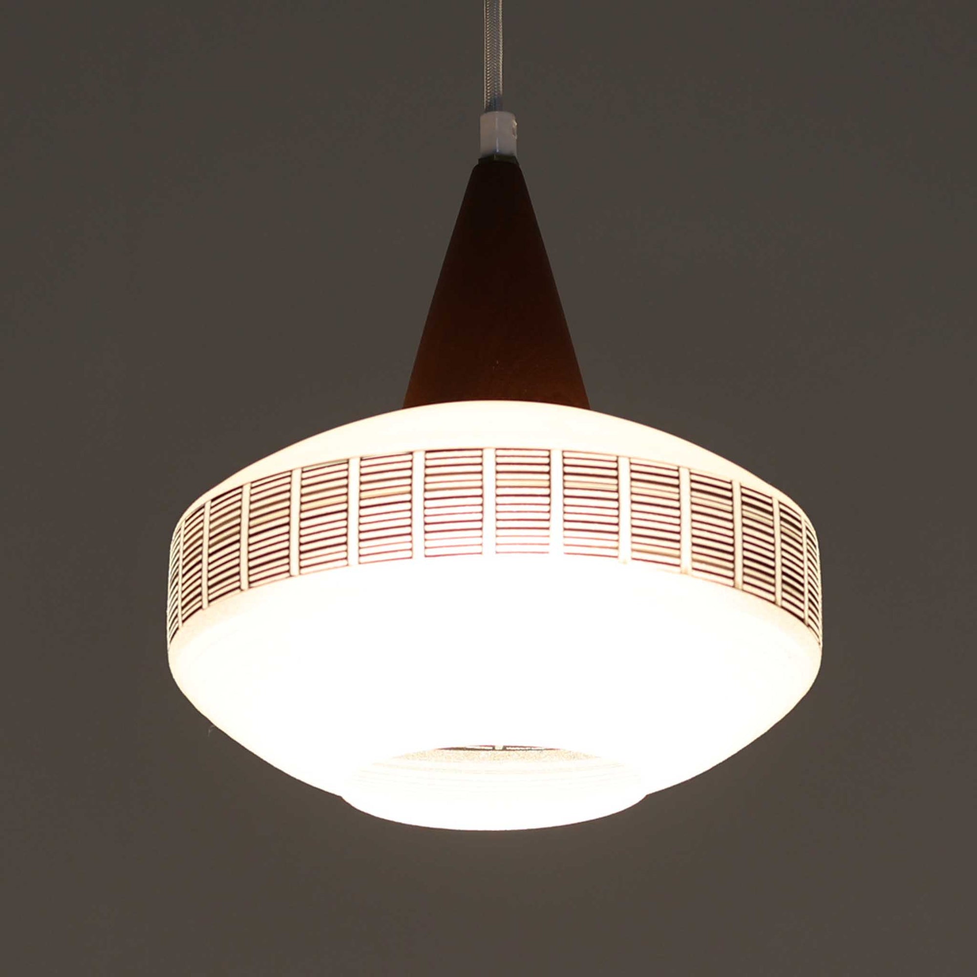 ガラスシェードに幾何学模様の装飾をあしらい、上部にあたたかみのあるウッドパーツを組み合わせた直径24cmのペンダントライトで、素材のコントラストが北欧ビンテージらしい個性を引き立てています。柔らかく広がる乳白ガラスが空間をやさしく照らし、ダイニングやキッチンカウンター、玄関灯としても取り入れやすいサイズ感です。シンプルながら手仕事を感じさせる仕上げや経年による素材の深みが魅力で、単体でアクセントにするほか、複数灯でリズムをつけたコーディネートにもおすすめです。