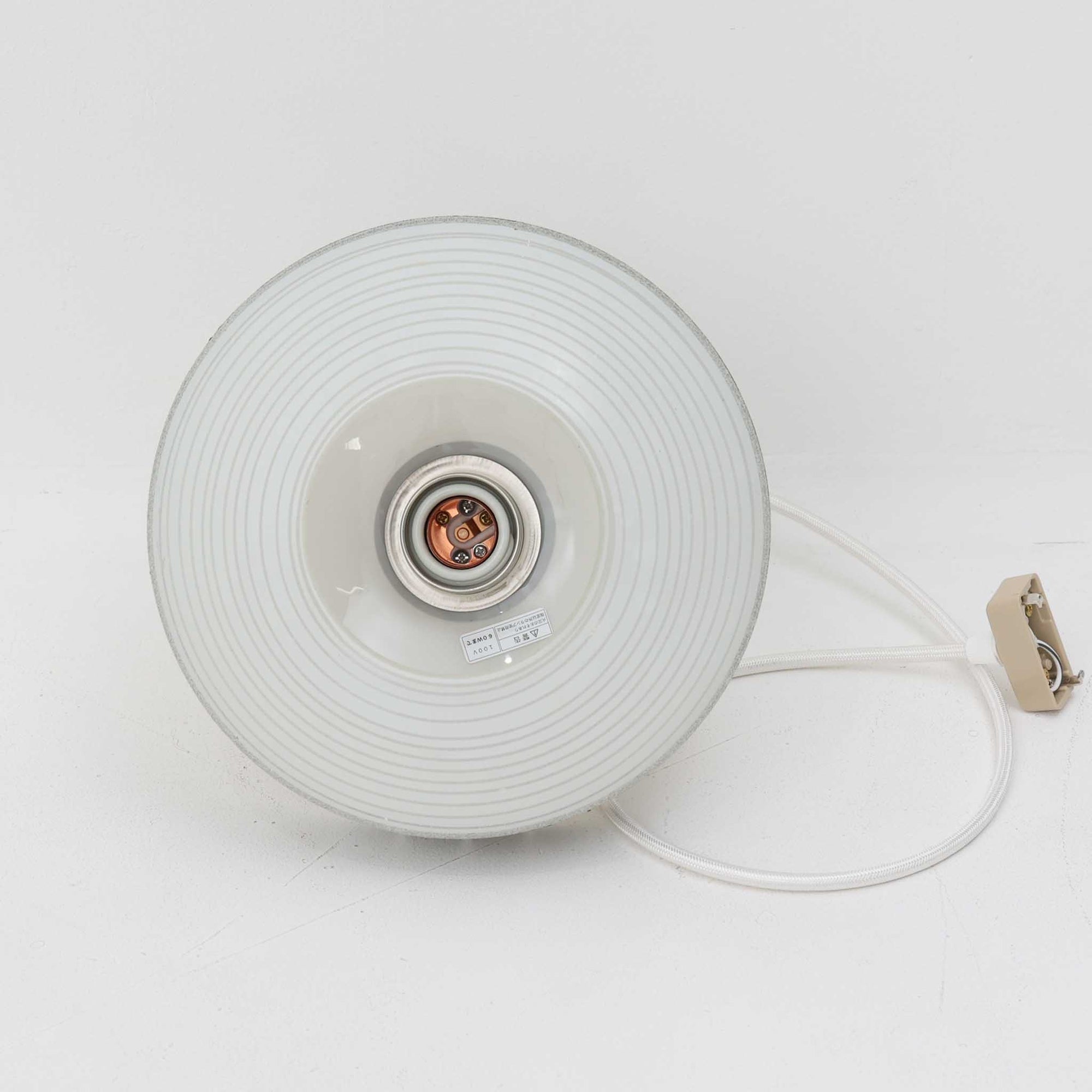 ガラスシェードに幾何学模様の装飾をあしらい、上部にあたたかみのあるウッドパーツを組み合わせた直径24cmのペンダントライトで、素材のコントラストが北欧ビンテージらしい個性を引き立てています。柔らかく広がる乳白ガラスが空間をやさしく照らし、ダイニングやキッチンカウンター、玄関灯としても取り入れやすいサイズ感です。シンプルながら手仕事を感じさせる仕上げや経年による素材の深みが魅力で、単体でアクセントにするほか、複数灯でリズムをつけたコーディネートにもおすすめです。