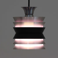 Carl ThoreがGranhaga Metallindustriで手掛けた直径15cmの小ぶりなペンダントライトで、段状に重ねたアルミシェードが光を柔らかく拡散し、点灯時には上下方向へ美しいグラデーションを生み出す北欧ビンテージ品です。繊細なヘアライン仕上げとブラックパーツのコントラストがモダンな印象を与え、キッチンカウンターや小空間のアクセント照明としてはもちろん、複数灯を並べたコーディネートにも最適です。コンパクトながら彫刻的なフォルムが存在感を放ち、経年で深まった質感がビンテージならではの魅力を際立たせています。