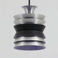 Carl ThoreがGranhaga Metallindustriで手掛けた直径15cmの小ぶりなペンダントライトで、段状に重ねたアルミシェードが光を柔らかく拡散し、点灯時には上下方向へ美しいグラデーションを生み出す北欧ビンテージ品です。繊細なヘアライン仕上げとブラックパーツのコントラストがモダンな印象を与え、キッチンカウンターや小空間のアクセント照明としてはもちろん、複数灯を並べたコーディネートにも最適です。コンパクトながら彫刻的なフォルムが存在感を放ち、経年で深まった質感がビンテージならではの魅力を際立たせています。