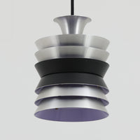 Carl ThoreがGranhaga Metallindustriで手掛けた直径15cmの小ぶりなペンダントライトで、段状に重ねたアルミシェードが光を柔らかく拡散し、点灯時には上下方向へ美しいグラデーションを生み出す北欧ビンテージ品です。繊細なヘアライン仕上げとブラックパーツのコントラストがモダンな印象を与え、キッチンカウンターや小空間のアクセント照明としてはもちろん、複数灯を並べたコーディネートにも最適です。コンパクトながら彫刻的なフォルムが存在感を放ち、経年で深まった質感がビンテージならではの魅力を際立たせています。