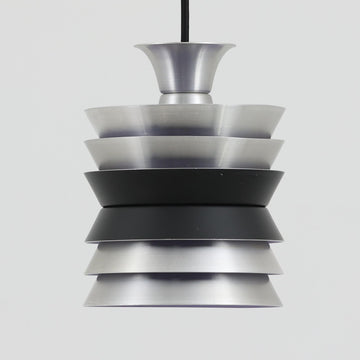 Carl ThoreがGranhaga Metallindustriで手掛けた直径15cmの小ぶりなペンダントライトで、段状に重ねたアルミシェードが光を柔らかく拡散し、点灯時には上下方向へ美しいグラデーションを生み出す北欧ビンテージ品です。繊細なヘアライン仕上げとブラックパーツのコントラストがモダンな印象を与え、キッチンカウンターや小空間のアクセント照明としてはもちろん、複数灯を並べたコーディネートにも最適です。コンパクトながら彫刻的なフォルムが存在感を放ち、経年で深まった質感がビンテージならではの魅力を際立たせています。