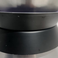 Carl ThoreがGranhaga Metallindustriで手掛けた直径15cmの小ぶりなペンダントライトで、段状に重ねたアルミシェードが光を柔らかく拡散し、点灯時には上下方向へ美しいグラデーションを生み出す北欧ビンテージ品です。繊細なヘアライン仕上げとブラックパーツのコントラストがモダンな印象を与え、キッチンカウンターや小空間のアクセント照明としてはもちろん、複数灯を並べたコーディネートにも最適です。コンパクトながら彫刻的なフォルムが存在感を放ち、経年で深まった質感がビンテージならではの魅力を際立たせています。