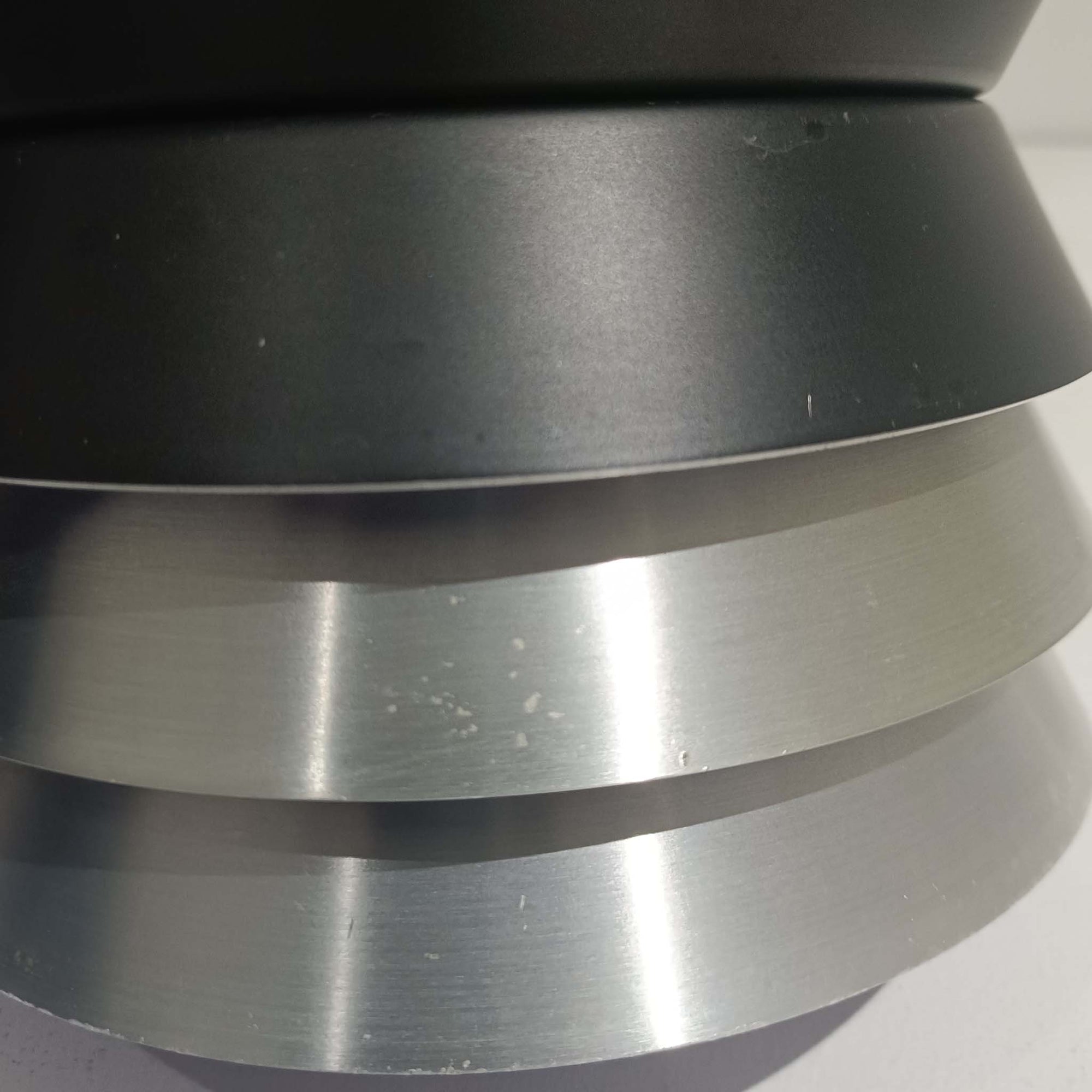 Carl ThoreがGranhaga Metallindustriで手掛けた直径15cmの小ぶりなペンダントライトで、段状に重ねたアルミシェードが光を柔らかく拡散し、点灯時には上下方向へ美しいグラデーションを生み出す北欧ビンテージ品です。繊細なヘアライン仕上げとブラックパーツのコントラストがモダンな印象を与え、キッチンカウンターや小空間のアクセント照明としてはもちろん、複数灯を並べたコーディネートにも最適です。コンパクトながら彫刻的なフォルムが存在感を放ち、経年で深まった質感がビンテージならではの魅力を際立たせています。