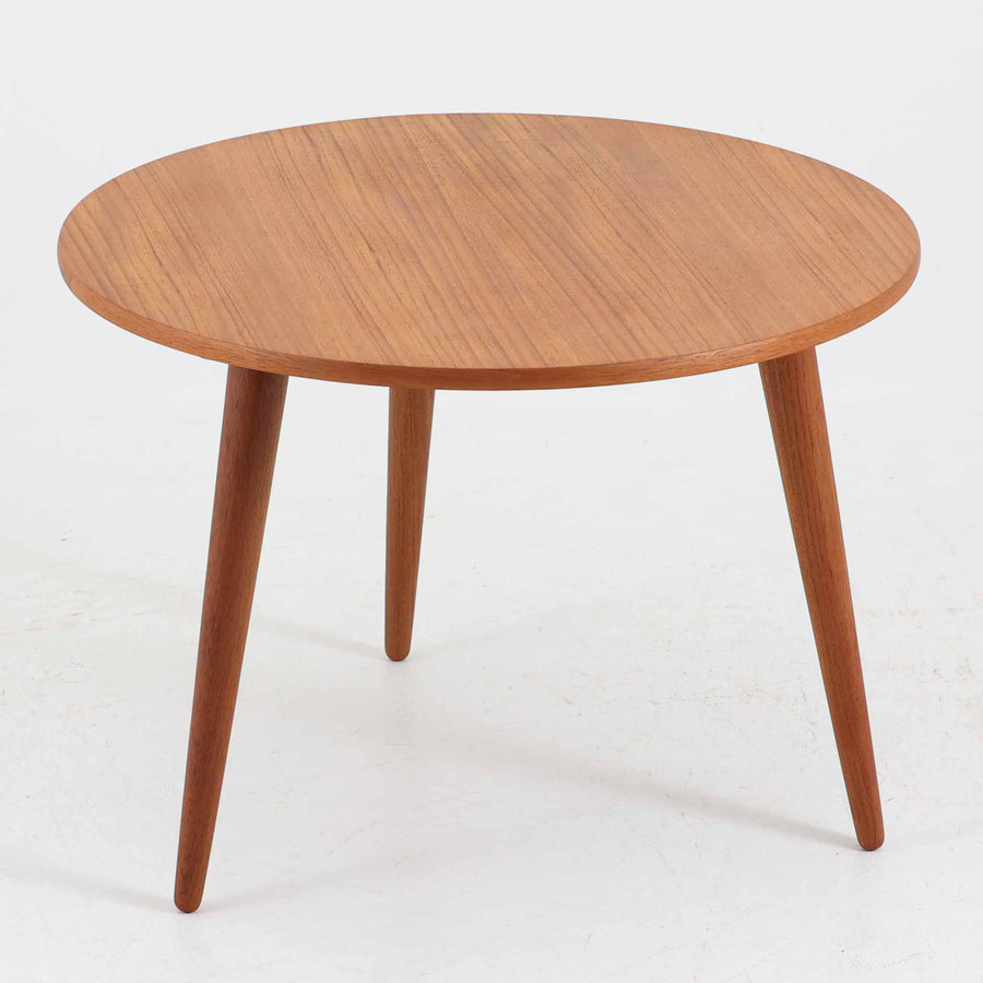 デンマークの巨匠Hans J. Wegner（ハンス・J・ウェグナー）がAndreas Tuck社のためにデザインした「AT8」円形センターテーブルです。チーク材による滑らかな天板と、3本脚の軽やかな構造が特徴で、美しくテーパーのついた脚部が全体に上品な印象を与えます。脚は木製のねじ込み構造になっており、工具を使わずに着脱が可能です。こうしたディテールにもビンテージ期ならではの職人技が感じられます。脚部までチーク材が使用された希少なタイプで、素材の統一感と温かみのある質感が際立ちます。ウェグナーらしいシンプルで機能的な造形と、経年により深みを増したチークの風合いが融合し、リビング空間に上質な北欧のぬくもりを添える一台です。